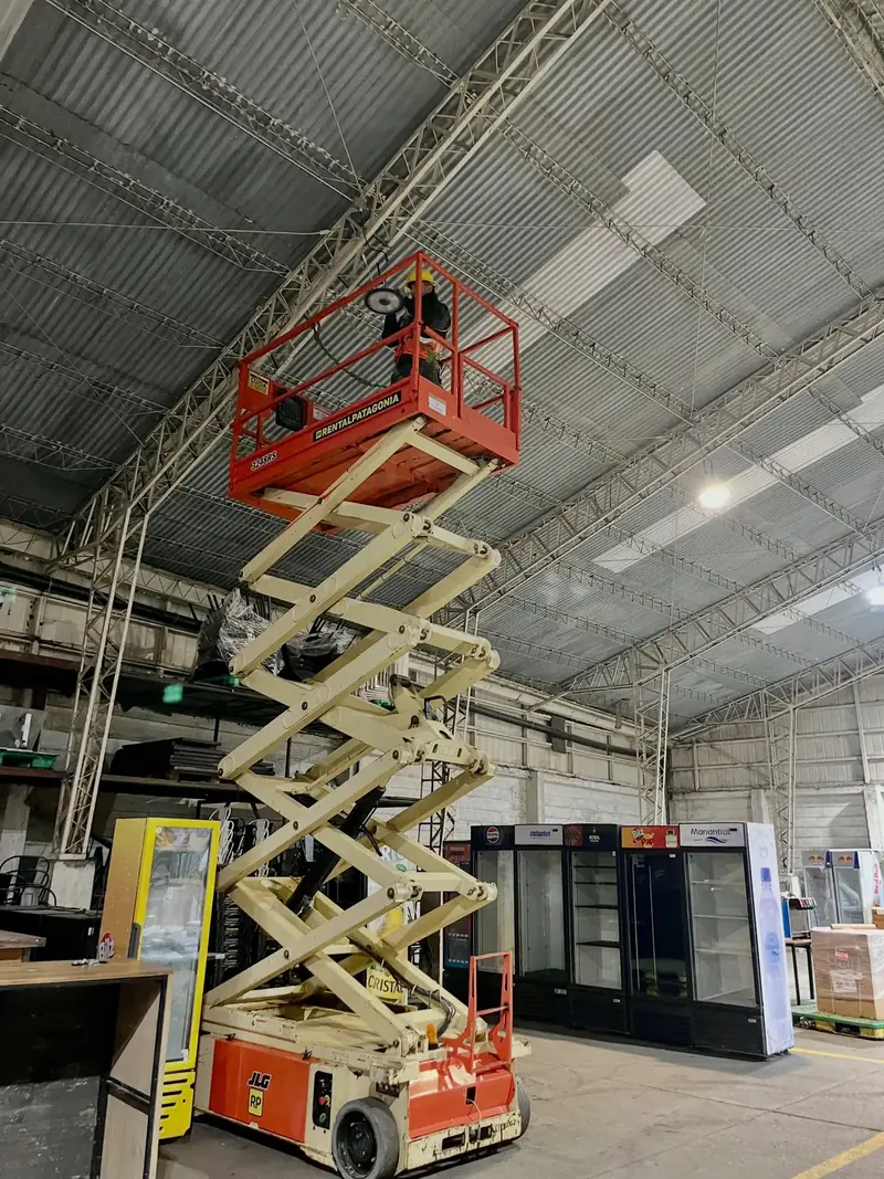 Supervisión de un trabajo en altura con plataforma elevadora dentro de un galpón